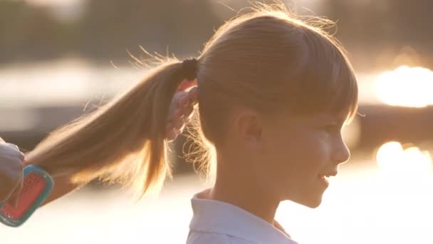Mutter kämmt Haare ihrer Tochter im Sommerpark mit Bürste — Stockvideo