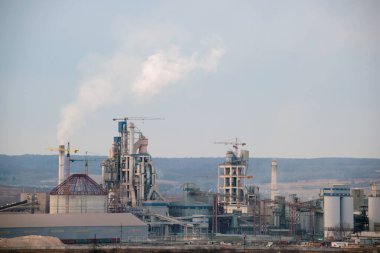 Yüksek fabrika yapısı olan çimento fabrikası ve endüstriyel üretim bölgesinde kule vinçleri var. Üretim, küresel sanayi ve hava kirliliği kavramı