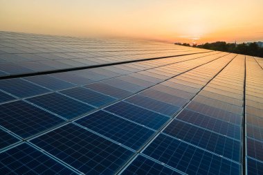 Mavi fotovoltaik güneş panelleri gün batımında temiz ekolojik elektrik üretmek için çatıya monte edildi. Yenilenebilir enerji konsepti üretimi