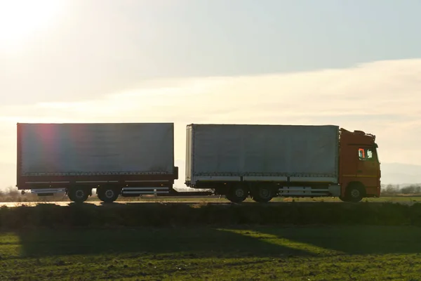Semi-vrachtwagen met lading aanhangwagen rijden op de snelweg vervoeren goederen in de avond. Levering transport en logistiek concept — Stockfoto