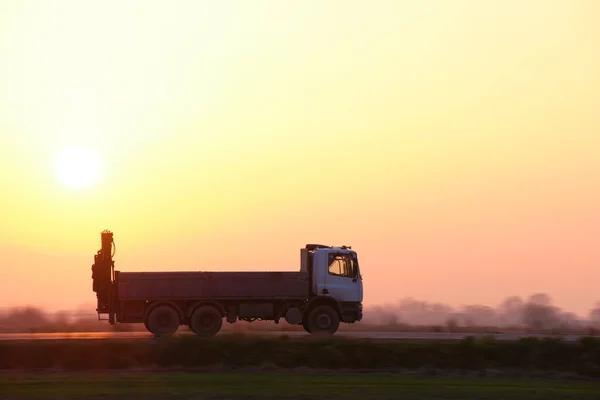 Vrachtwagen dumpen rijden op de snelweg vervoeren goederen in de avond. Levering transport en logistiek concept — Stockfoto