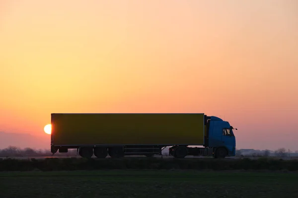 Semi-vrachtwagen met lading aanhangwagen rijden op de snelweg vervoeren goederen in de avond. Levering transport en logistiek concept — Stockfoto