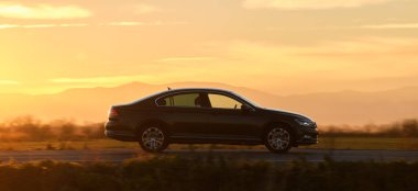 Gün batımında şehir içi yolda hızlı giden bir araba. Akşamları otoyol trafiği