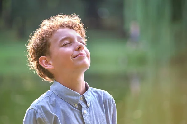 Маленький счастливый мальчик отдыхает в летнем парке. Позитивный ребенок наслаждается летом на свежем воздухе. Концепция детского благополучия — стоковое фото
