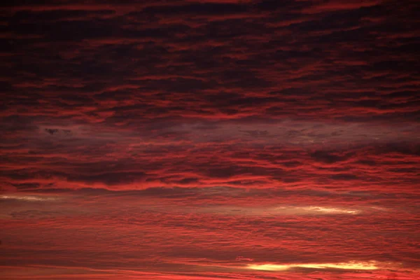 Яскраве барвисте небо заходу сонця з яскравими гладкими хмарами, освітленими встановленням сонячного світла, що поширюється на горизонт — стокове фото