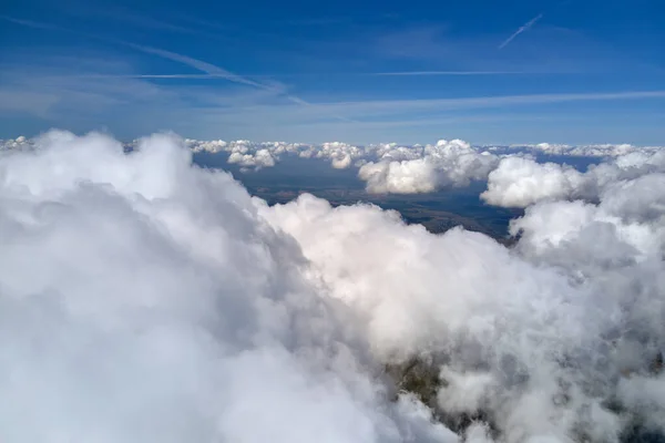 Vista aérea da janela do avião em alta altitude da terra coberta com nuvens de cúmulo inchadas brancas — Fotografia de Stock