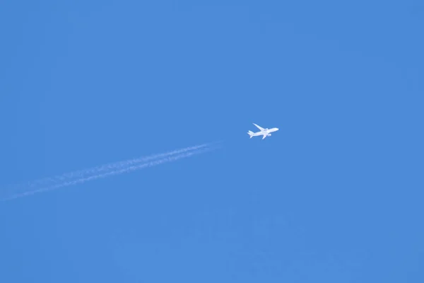 Aereo a reazione passeggeri distanti che volano in alta quota su cielo blu chiaro lasciando tracce di fumo bianco di contrail dietro. Concetto trasporto aereo — Foto Stock