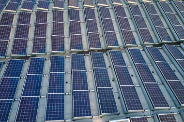 Sanayi binasının çatısına yeşil ekolojik elektrik üretmek için monte edilmiş mavi fotovoltaik panelli güneş enerjisi santralinin hava görüntüsü. Sürdürülebilir enerji konsepti üretimi