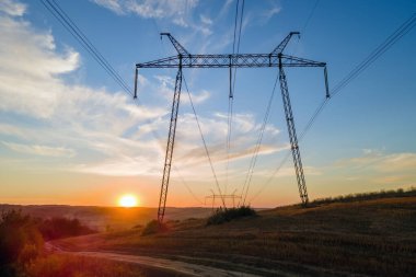 Gün batımında elektrik hatları olan yüksek voltaj kulesi. Elektrik aktarımı