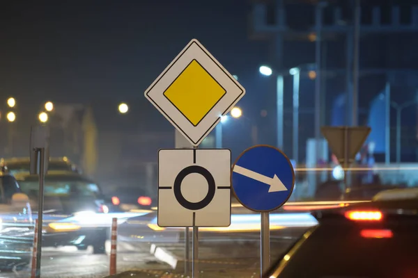 Ранкові дорожні знаки з розмитими автомобілями на міському вуличному трафіку вночі. Концепція міського транспорту — стокове фото