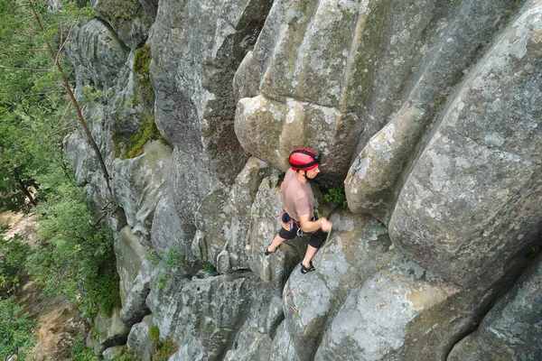 Forte alpinista do sexo masculino escalando parede íngreme de montanha rochosa. Esportista superando rota difícil. Envolvendo-se em conceito de passatempo esportivo extremo — Fotografia de Stock