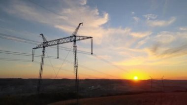 Güneş doğarken elektrik hatları olan yüksek voltaj kulesinin koyu gölgesi. Elektrik enerjisi konsepti aktarımı