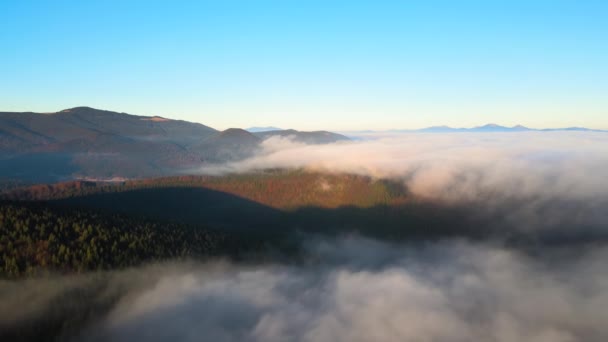 Luftaufnahme des farbenfrohen Sonnenaufgangs über weißem dichtem Nebel mit weit entfernten dunklen Silhouetten der Berghügel am Horizont — Stockvideo