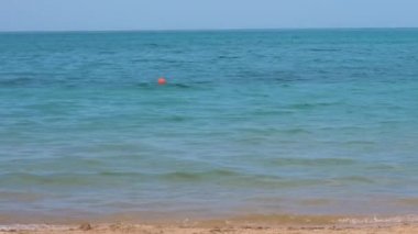 Yaz tatillerinde deniz kıyısında kumsalda yürüyen beyaz elbiseli mutlu bir kız çocuğu. Tatil konseptinde seyahat ve dinlenme