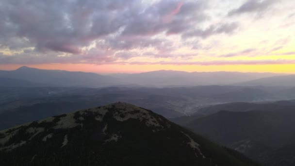 秋の日の出に森の松の木で覆われた霧の暗い山のピークと素晴らしい景色の空中ビュー。夜明けに光の輝きを持つ美しい野生の森 — ストック動画