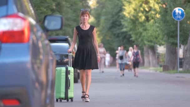 Молодая женщина-водитель загружает багажную сумку в машину. Концепция путешествий и отдыха — стоковое видео