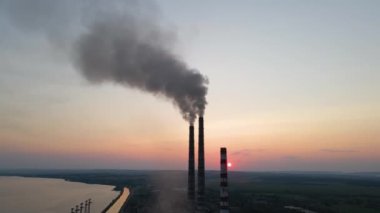 Kara dumanlı yüksek boruların hava görüntüsü gün batımında atmosferi kirletiyor. Fosil yakıt kavramına sahip elektrik enerjisi üretimi