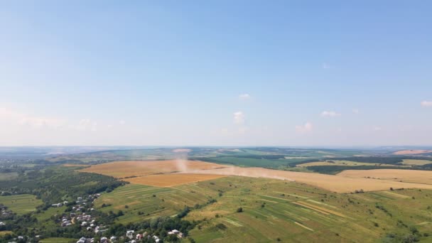 Vista aérea del camión de carga que conduce en el camino de tierra entre los campos de trigo agrícola haciendo mucho polvo. Transporte de grano después de ser cosechado por cosechadora durante la temporada de cosecha — Vídeos de Stock