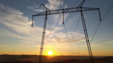 Güneş doğarken elektrik hatları olan yüksek voltaj kulesinin koyu gölgesi. Elektrik enerjisi konsepti aktarımı