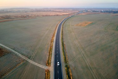 Gün batımında hızlı giden bulanık arabalı şehirlerarası yol manzarası. Akşamları otoban trafiğinin insansız hava aracı görüntüsü