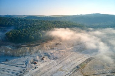 Kazı araçları ve çöp kamyonları ile inşaat endüstrisi için kireçtaşı malzemelerinin açık çukur madenciliğinin hava görüntüsü
