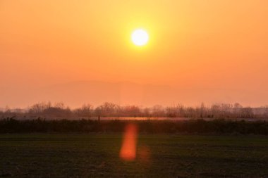 Güzel bir akşam panoramik manzarası. Gün batımında güneş batarken uzak dağ tepeleri ve asfalt yolda batıyor.