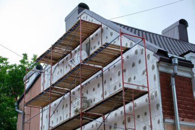 İnşaat iskelesi ile yenilenen bina cephesi. Enerji tasarruflu ev için köpük çarşaflı duvar yalıtımı