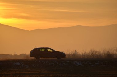 Gün batımında şehir içi yolda hızlı giden bir araba. Akşamları otoyol trafiği
