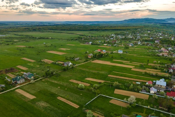 Vista aérea del paisaje de campos agrícolas verdes cultivados con cultivos en crecimiento y casas de pueblo distantes — Foto de Stock