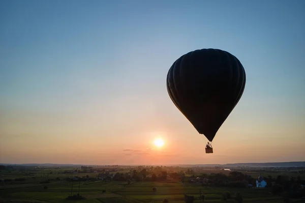 日没時に田舎を飛んでいる大きな熱気球の空中ビュー — ストック写真