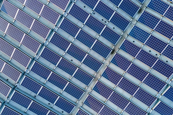 Vista aérea de paneles solares fotovoltaicos azules montados en el techo de un edificio industrial para producir electricidad ecológica verde. Producción del concepto de energía sostenible — Foto de Stock