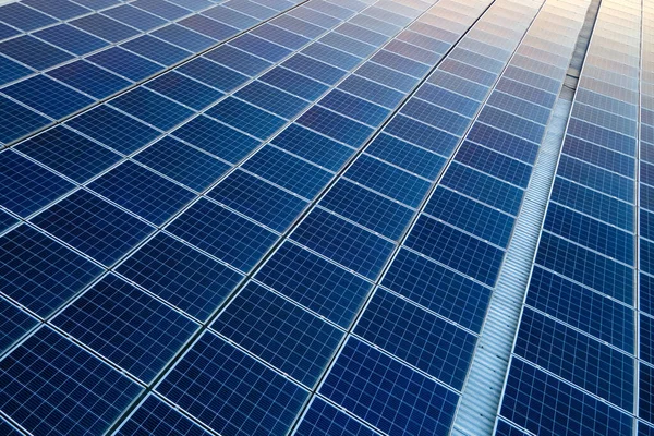 Paneles solares fotovoltaicos azules montados en el techo del edificio para producir electricidad ecológica limpia al atardecer. Concepto de producción de energías renovables — Foto de Stock