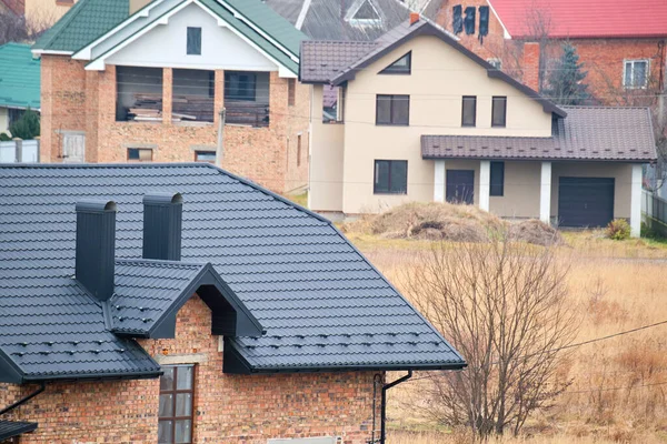 Camino sul tetto della casa coperto con tegole metalliche in costruzione. Copertura piastrellata di edificio. Sviluppo immobiliare — Foto Stock