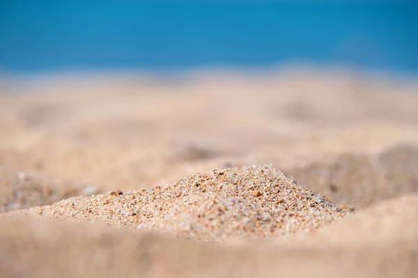 Close up of clean yellow sand surface covering seaside beach with blue sea water on background. Travel and vacations concept — Stock Photo, Image