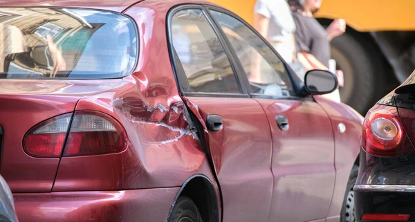 Dented car with damaged body parked on city street side. Road safety and vehicle insurance concept — Stockfoto