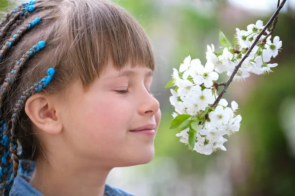 Glad barn flicka njuter söt doft av vita körsbär träd blommande blommor på solig dag i vår trädgård — Stockfoto