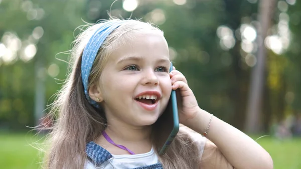 여름 공원에서 휴대폰으로 대화하고 있는 행복 한 어린 소녀 — 스톡 사진