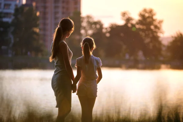 Happy mother and daughter standing together looking at building under construction dreaming about their future home at sunset. Family love and relationship concept — Stock Photo, Image