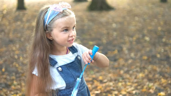 Liten glad barn flicka blåser såpbubblor utomhus i sommarparken — Stockfoto