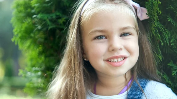 여름 공원에서 행복하게 웃는 카메라 앞에 서 있는 예쁜 소녀의 모습 — 스톡 사진