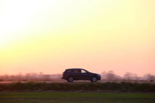 SUV coche de conducción rápida en la carretera interurbana al atardecer. Tráfico por carretera por la noche — Foto de Stock