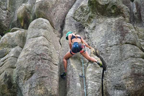Junge Frau klettert steile Felswand hinauf. Bergsteigerin überwindet anspruchsvolle Route Engagement im Extremsportkonzept — Stockfoto