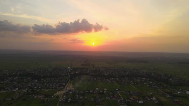 Vista aérea del paisaje de las casas de pueblo y campos agrícolas cultivados verdes distantes con cultivos en la noche de verano brillante — Vídeos de Stock