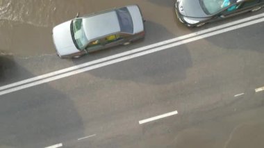 Şiddetli yağmurdan sonra sel basmış caddede giden arabalarla şehir trafiğinin hava görüntüsü. Yol drenaj sistemi ile ilgili sorunlar