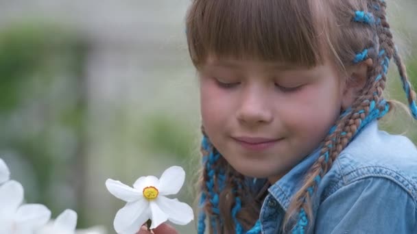 Heureuse fille enfant jouant dans le jardin d'été profitant d'un doux parfum de fleurs de narcisse blanches le jour ensoleillé — Video
