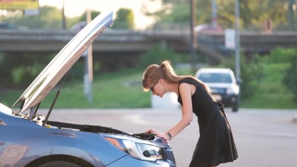 Conductora desconcertada de pie en una calle de la ciudad cerca de su coche con capucha reventada mirando el motor roto — Vídeos de Stock