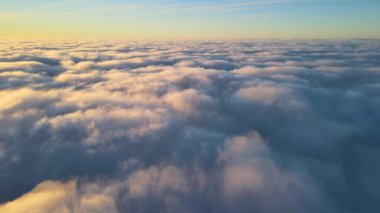 Yükseklerden gökyüzü manzarası. Akşamları yoğun, kabarık kümülüs bulutları uçuşuyor. Uçak penceresinden gün batımı inanılmaz.