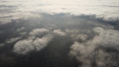 Gün batımında yağmur fırtınasından önce bulutlarla kaplı uzak şehrin yüksek irtifasından gelen hava manzarası. Bulutlu havada uçak manzarası