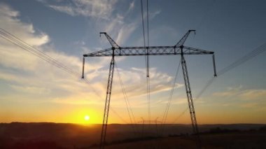 Güneş doğarken elektrik hatları olan yüksek voltaj kulesinin koyu gölgesi. Elektrik enerjisi konsepti aktarımı