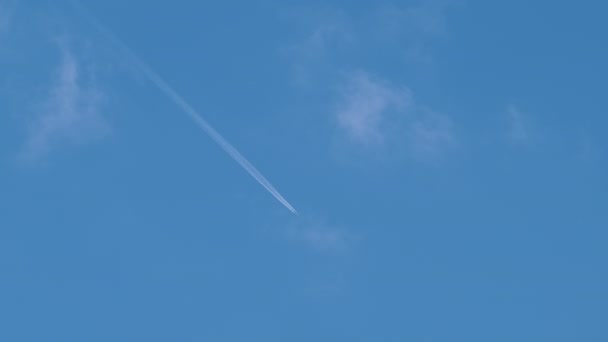 Aereo a reazione passeggeri distanti che vola in alta quota sul cielo blu con nuvole bianche lasciando tracce di fumo di contrail dietro. Concetto di viaggio aereo — Video Stock